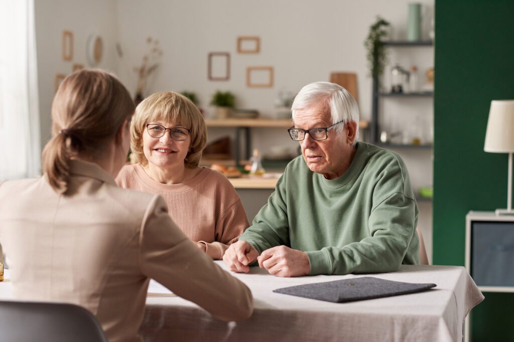 Deux personnes âgées discutant avec une courtière immobilière de la vente de leur maison